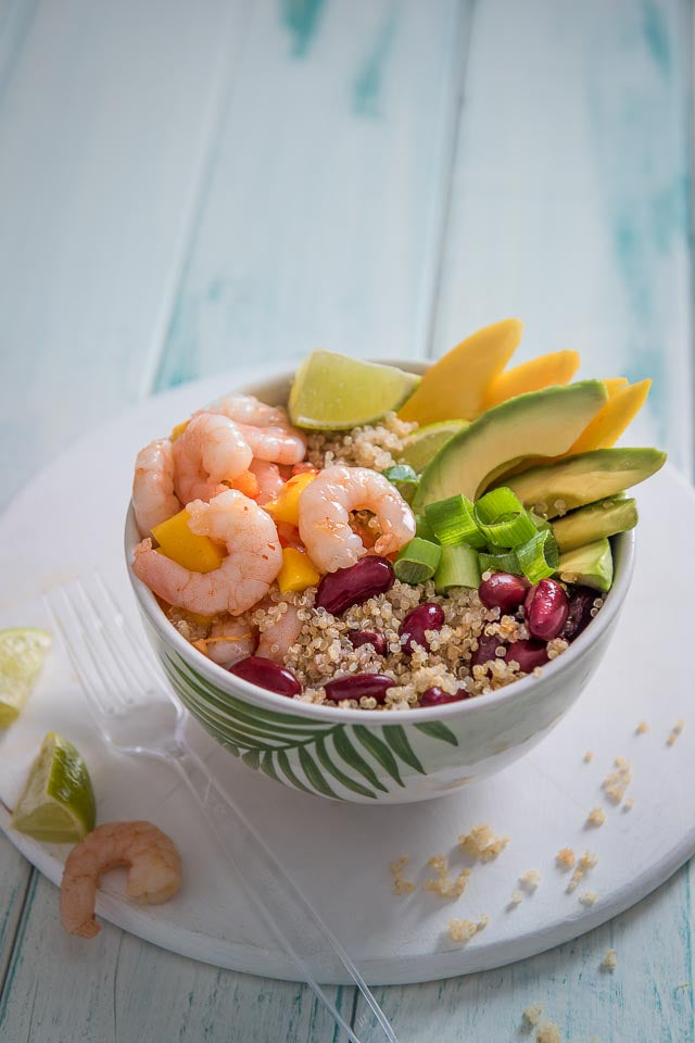 Bowl of quinoa topped with prawns, slices of avocado and red kidney beans