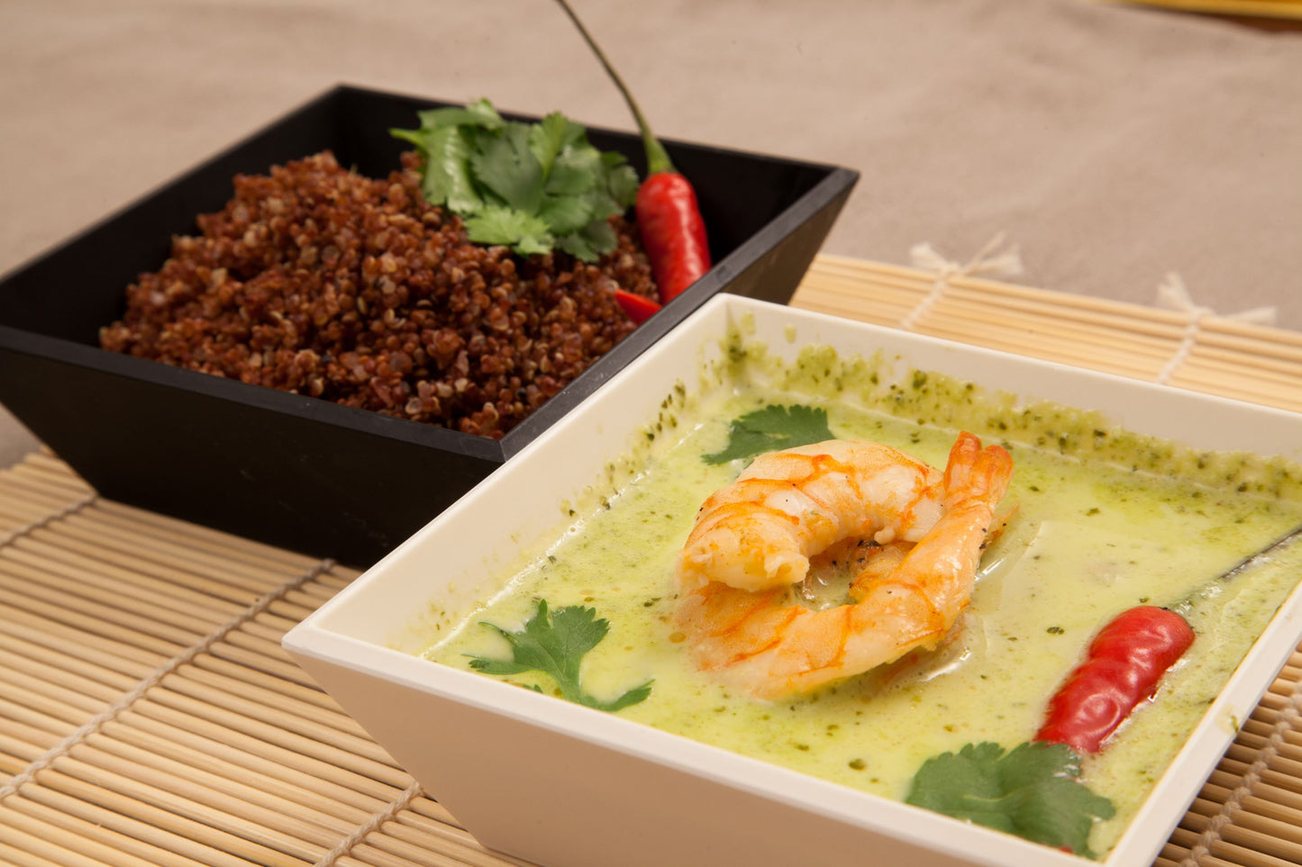 Two bowls, one with red quinoa and another bowl of prawn green thai curry