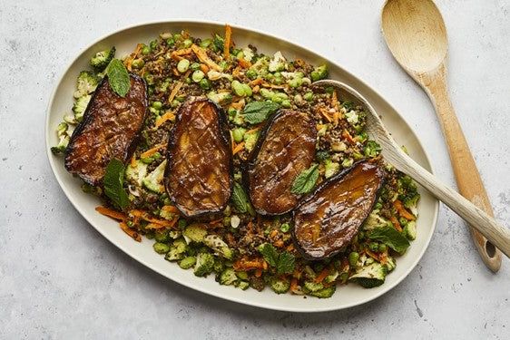 Plate filled with quinoa and colourful veg, 2 roasted aubergines placed on top 