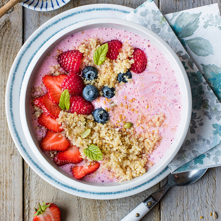 pink smoothie bowl topped with quinoa and fruit 