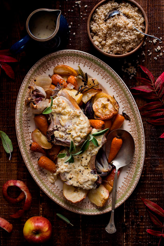 Large plate of roasted vegetables, potatoes and pork next to a bowl of quinoa