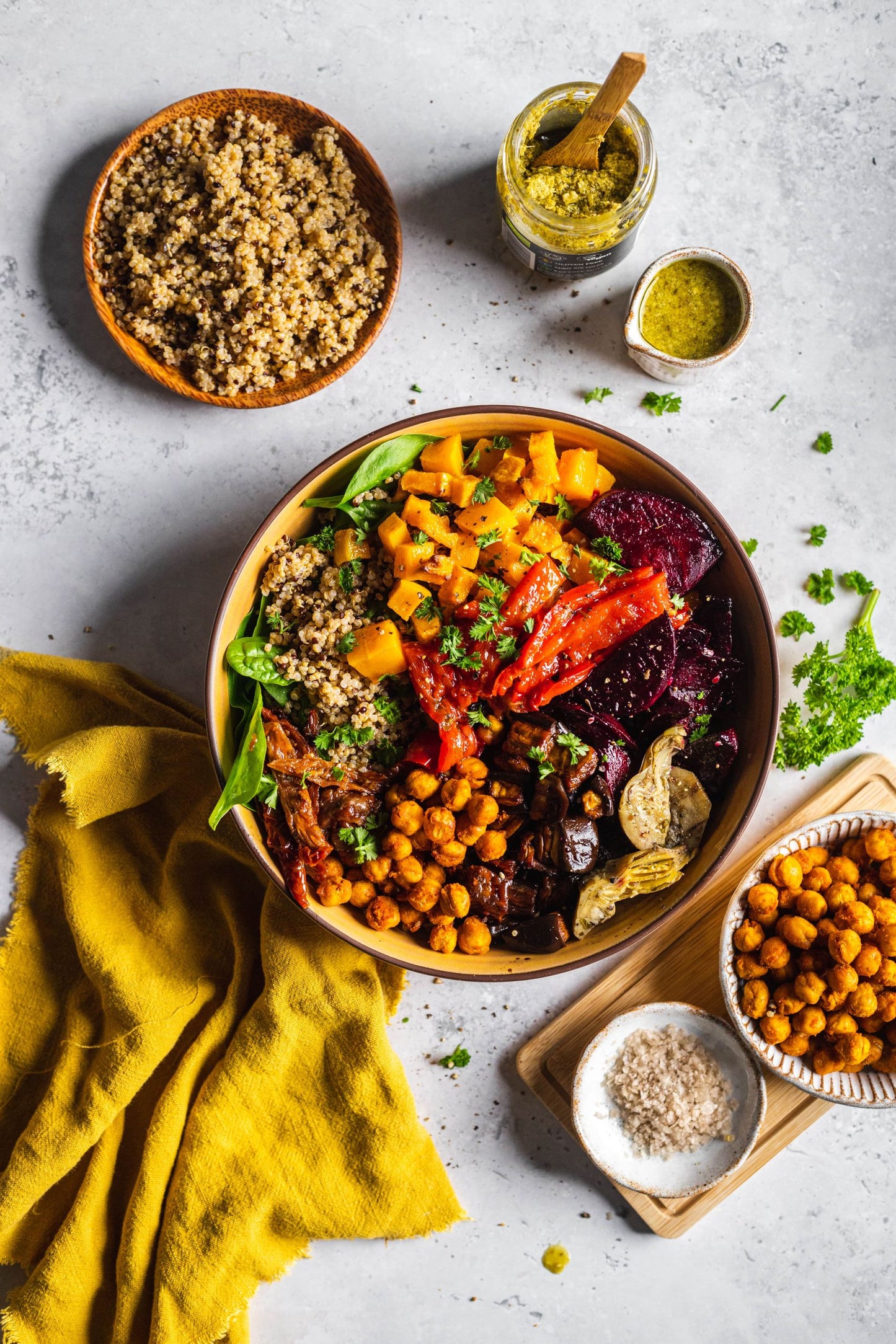 Bowl filled with quinoa, butternut squash, beetroot and chickpeas. Jar of pesto on the side and a bowl of quinoa. 