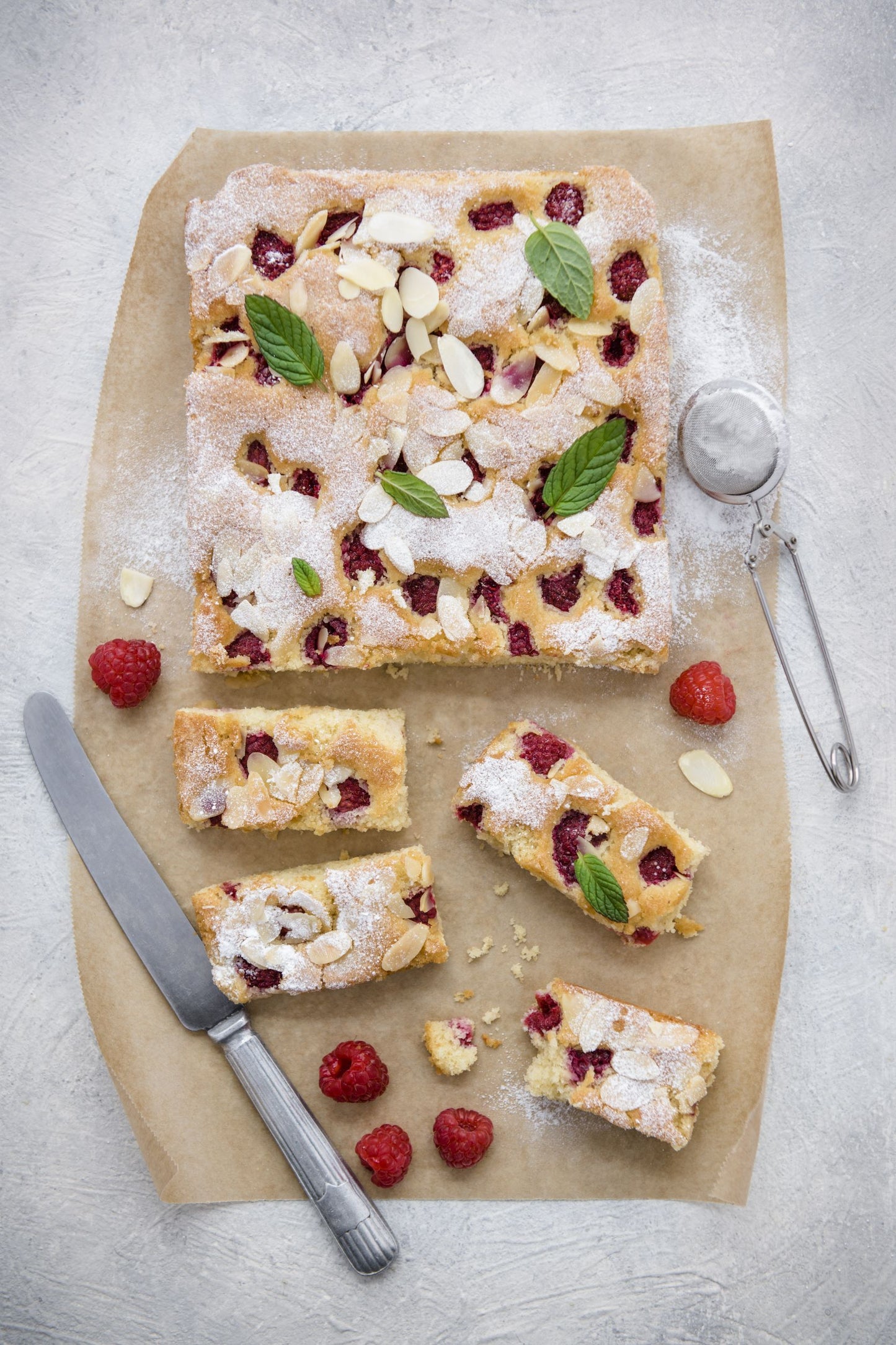 Baking sheet with quinoa, raspberry and almond cake, dusted with icing sugar and fresh raspberries 