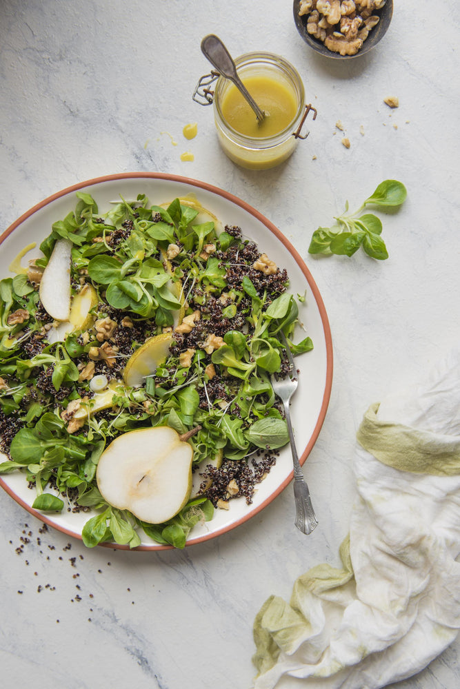 Bowl of quinoa salad with fennel, pears and a jar of mustard dressing 