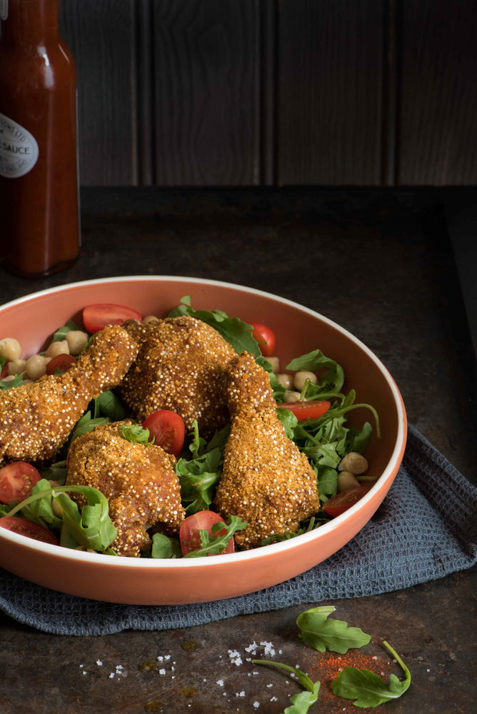 bowl of quinoa fried chicken on top of salad