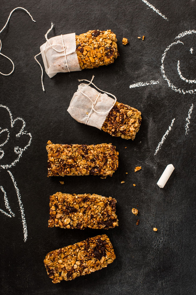Black chalk background with 5 quinoa, chocolate and granola bars in a line. 