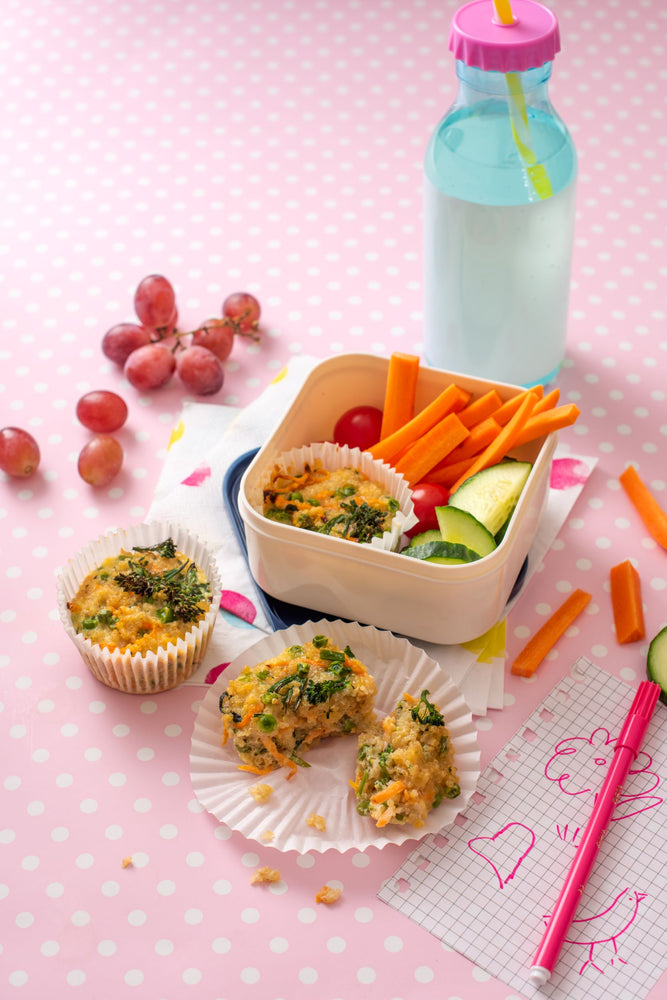 Lunch box packed with cheesy quinoa and broccoli cups, carrots and cucumber 