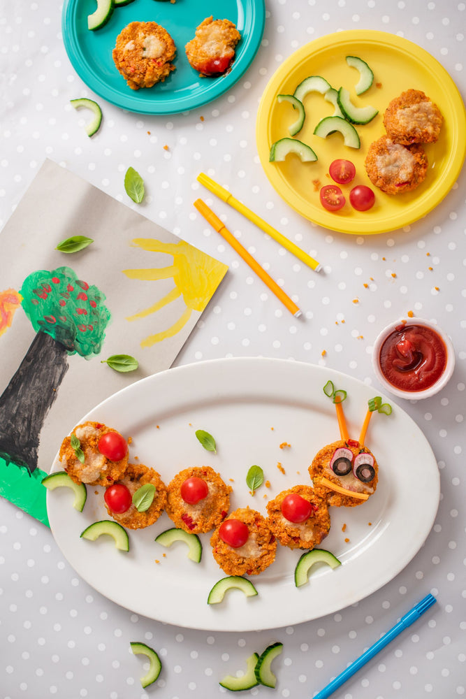 Plate of quinoa pizza bites shaped like a caterpillar with cucumber legs