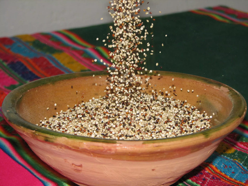 bowl of quinoa with quinoa being poured into it 