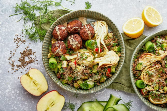 Quinoa and fennel salad with falafel on the side. Cut halves of an apple on the side of the bowl