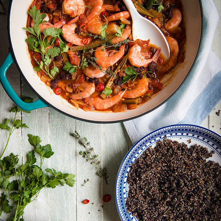 Bowl of black quinoa next to a pot of prawn gumbo 