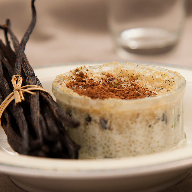 Jar of quinoa rice pudding with a sprinkling of cinnamon and sticks of vanilla pods 