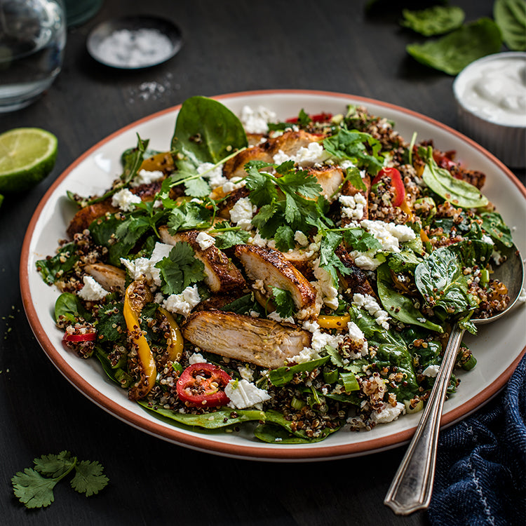 Plate of quinoa mixed with salad, slices of chili and chicken 